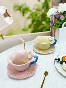 Detail of pouring tea into a ceramic flower petal cup with relief floral patterns