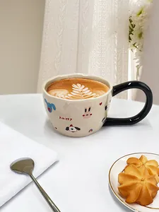 Vista superior de una taza de cerámica crema con dibujos animados y arte latte suave