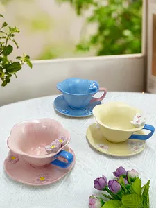 Detailed overhead view of ceramic coffee cups with 3D floral relief and colorful handles