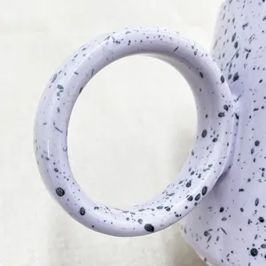 Macro detail of lavender ceramic mug with black ink splatter and oversized circular handle