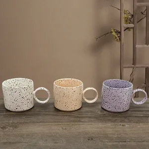 Handmade ceramic splash ink coffee mugs with unique large round handles on wooden table
