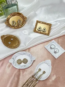 Macro detail of geometric stud earrings and pearl jewelry on vintage display trays