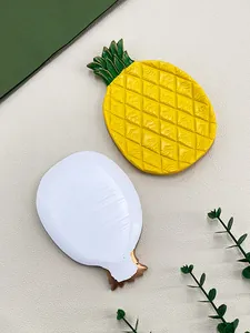 Detail van decoratieve ananas schaal met gele schubtextuur en groene bladaccenten