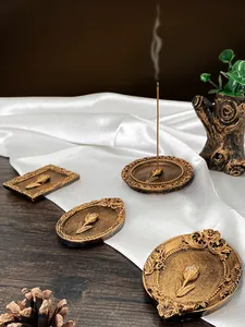 Macro detail of vintage gold incense holders with tulip relief on white silk background