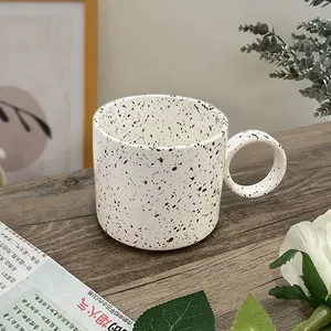 Artistic handmade white ceramic coffee mug with black ink splash and round handle
