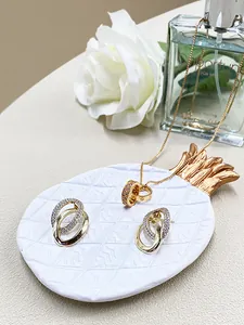 Detailopname van gouden in elkaar grijpende ringen ketting en oorbellen op dienblad