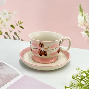 Detail of hand-painted ceramic coffee cup and saucer with vintage pink floral patterns