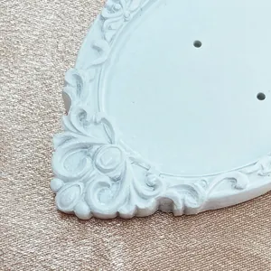 Close-up of white baroque relief earring display stand on champagne textured fabric