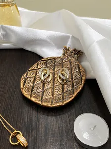 Detail van vergulde dubbele hoepeloorbellen met zirkonia op een decoratief dienblad in ananasvorm