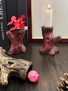 Dettaglio di candelabri in resina a forma di ceppo con trama realistica della corteccia e fiori