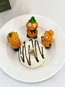 Κοντινή λήψη από ρητινένιες κολοκύθες Halloween σε λευκό πιάτο με ένα γλυκό ντόνατ δίπλα τους