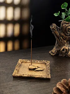 Close-up of golden vintage incense burner tray with embossed tulip holder on wood table
