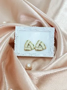 Close-up of geometric triangle earrings on vintage frame with silk and pearls
