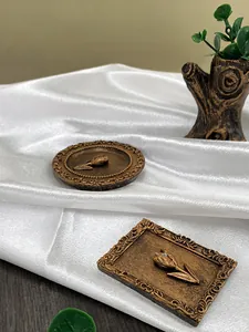 Macro shot of vintage gold tulip reliefs on ornate resin frames over white satin cloth