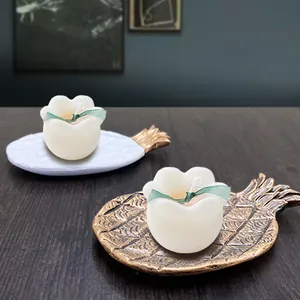 Bloemvormige geurkaarsen met linten op decoratieve schaaltjes in de vorm van ananas