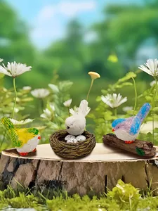 Dettaglio di tre uccelli in miniatura in resina con nido e uova per decoro giardino
