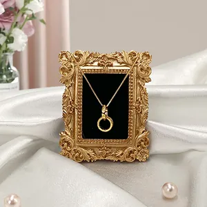 Collier en or avec pendentif à double boucle sur un cadre photo vintage et soie blanche