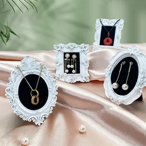 Mini cadres photo baroques blancs vintage pour bijoux sur un tissu de soie rose élégant