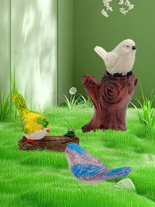 Dettaglio di tre uccellini decorativi in resina con piumaggio realistico da giardino