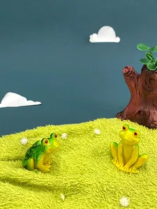 Detail view of two resin frog figurines with vibrant green gradient and red eyes decoration