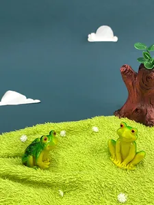 Detailed view of two cartoon frog resin miniatures on green lawn for garden decor