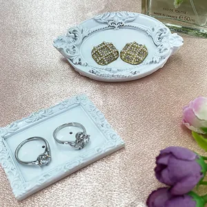 Retro jewelry display with gold earrings and silver rings on white relief tray