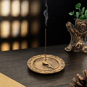 Vintage bronze tulip incense burner tray on a wooden table with soft smoke detail