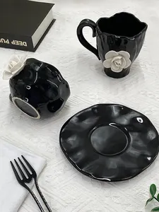 Detailed view of black ceramic coffee cup featuring a 3D white rose and wavy rim design