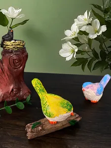 Dettaglio di figurine di uccelli in resina con piume realistiche su ceppi d'albero