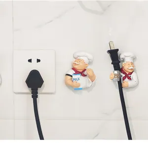 Chef shaped power plug holders for cable management on white marble tile wall background