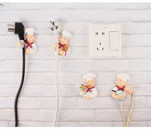 Detailed view of four chef-themed wall hooks organizing power plugs on a brick wall