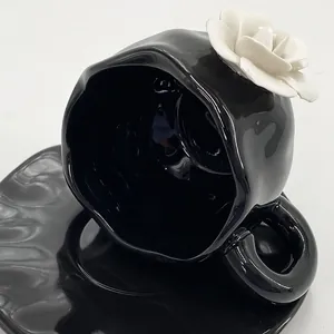 Close-up of black glossy ceramic coffee cup featuring a 3D white rose and wavy rim