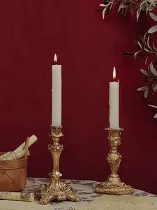 Close-up of golden vintage baroque candlesticks with ornate relief carvings and lit candles