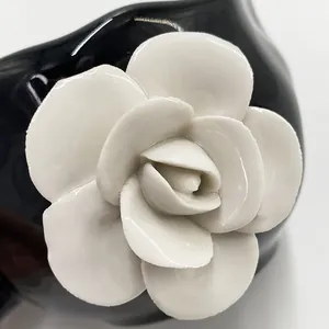 Macro detail of 3D white ceramic flower petals on a polished black coffee cup surface