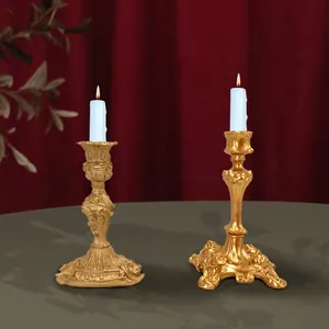 Baroque gold candle holders with intricate relief on a luxury red velvet background