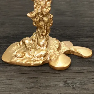 Nahaufnahme des goldenen Kerzenständer-Sockels mit organischer, lavaartiger Struktur