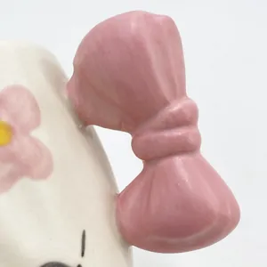 Dettaglio del manico a fiocco rosa 3D e della stampa floreale sulla tazza in ceramica