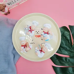 Detailed view of four cute resin chef wall hooks holding bread and milk on a pink base