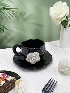 Detail of a 3D white rose on a black ceramic coffee cup with irregular saucer