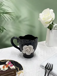 Detail of 3D white rose relief on black ceramic coffee mug with wavy rim and elegant handle