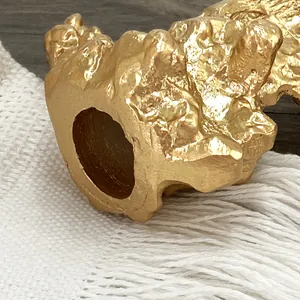 Detailansicht eines goldenen Kerzenhalters mit geschmolzener Lavatextur im Retrostil