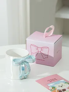 Dettaglio della tazza in ceramica perlata con manico a fiocco blu 3D e confezione regalo