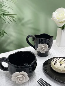 Macro view of 3D white ceramic camellia flowers on black handmade irregular coffee cups