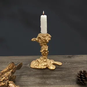 Künstlerischer matter Gold-Kerzenständer im Lava-Design auf dunklem Holz mit Kerze