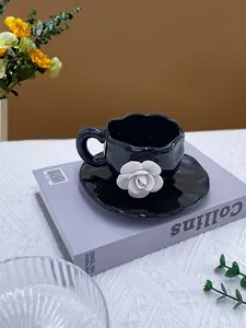 Detail view of the black ceramic coffee cup with 3D white rose relief and wavy rim