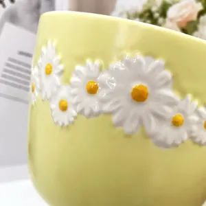 Detailed close-up of 3D embossed daisy flowers on a light yellow ceramic coffee mug