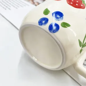 Detailopname van handgeschilderde keramische mok met aardbeien en handgreepdetail