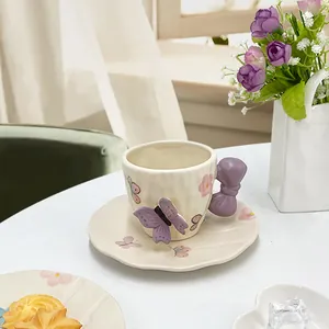 Dettaglio di tazzina in ceramica panna con manico a fiocco viola e farfalla 3D