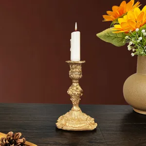 Close-up of golden vintage baroque candle holder with embossed texture and a white candle