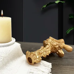 Detail von goldenem Kerzenhalter mit Felsstruktur auf einem dunklen Holztisch
